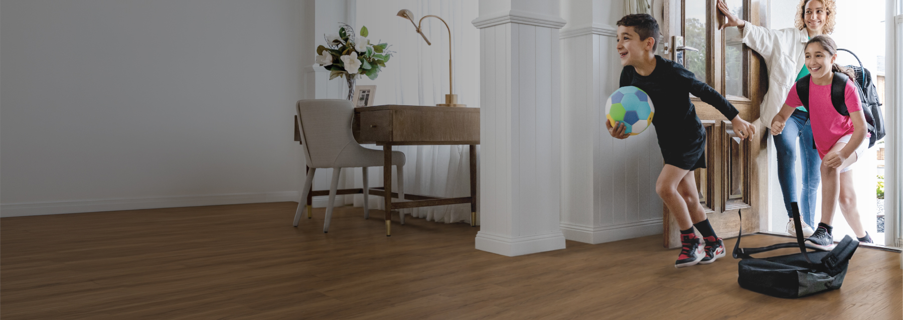 Family arriving home into a bright living space with timber flooring, showcasing Flooring Xtra's flooring collection.